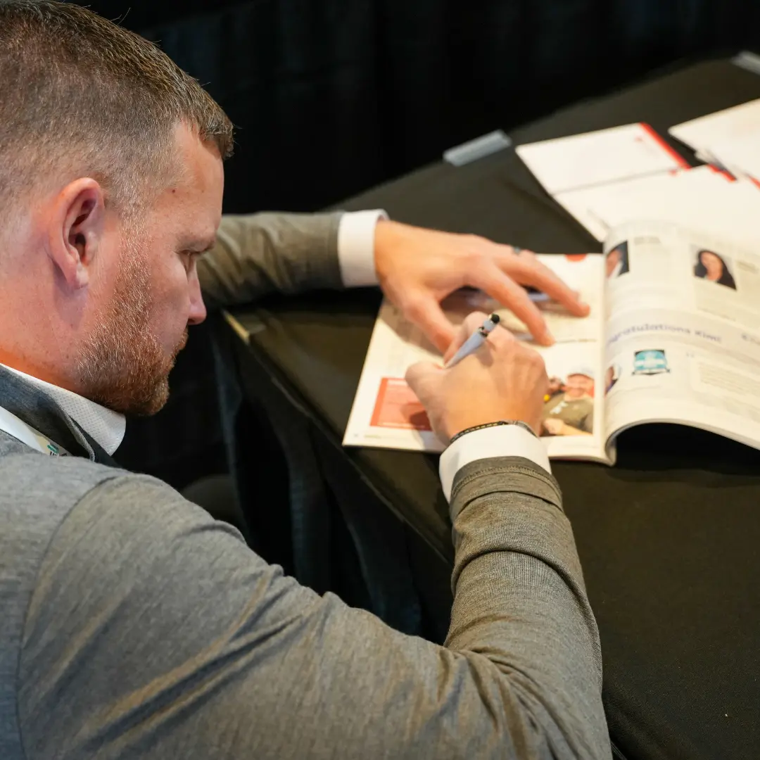 Dedicated Financial GBC CEO signing a magazine featuring his profile for company press and media