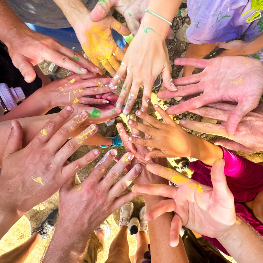 Paint-covered hands from a service trip representing Dedicated Financial GBC as a purpose-driven business